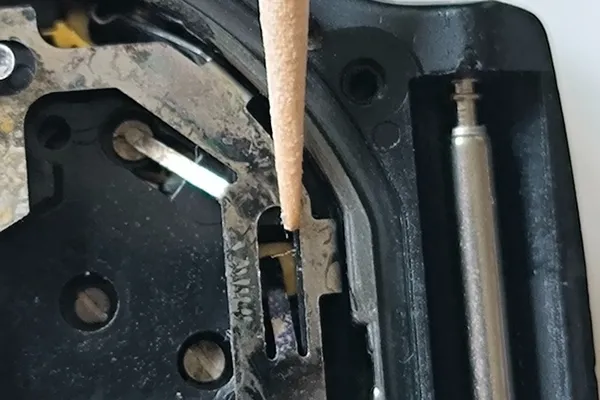 Toothpick pointing to the small metal tab that connects to the PCB.