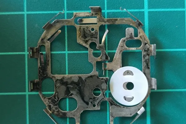 Inner side of top metal plate showing corrosion and insulator pad.